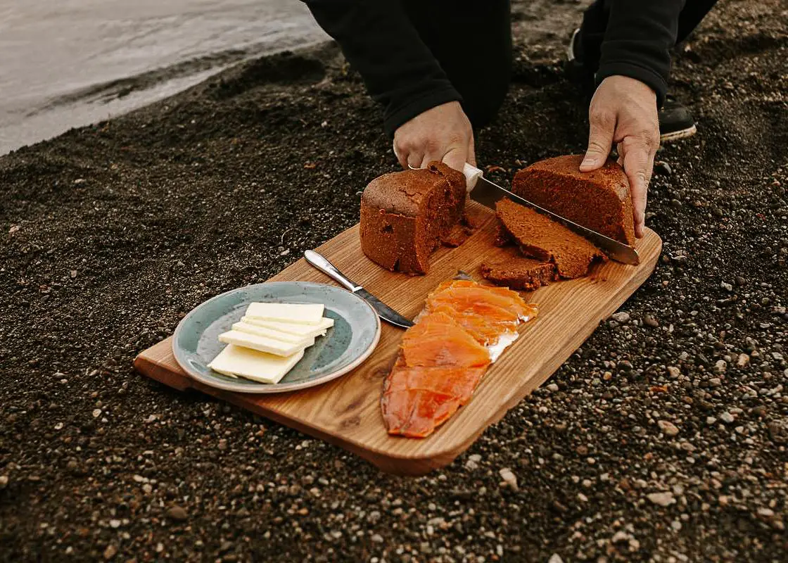 A man preparing traditional Icelandic rye bread with trout and butter near Laugarvatn Lake in Iceland