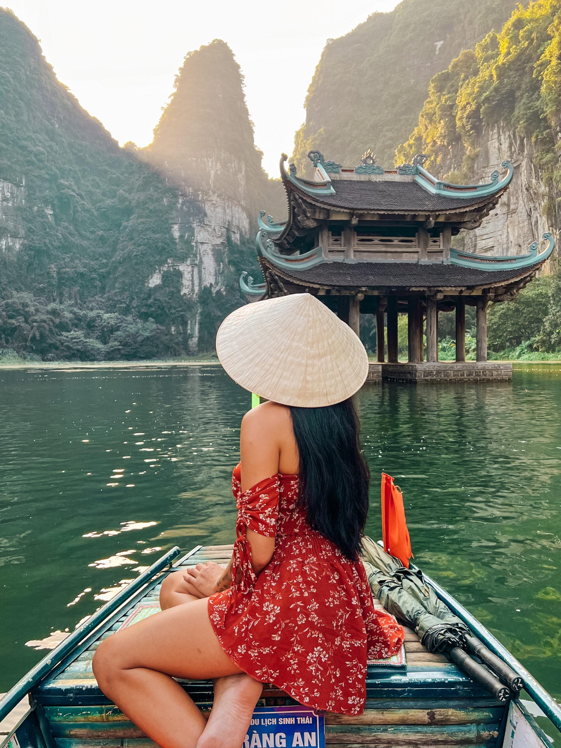 Vietnamese girl with a palm leaf hat on a boat in Trang An, Ninh Binh province, Vietnam.
