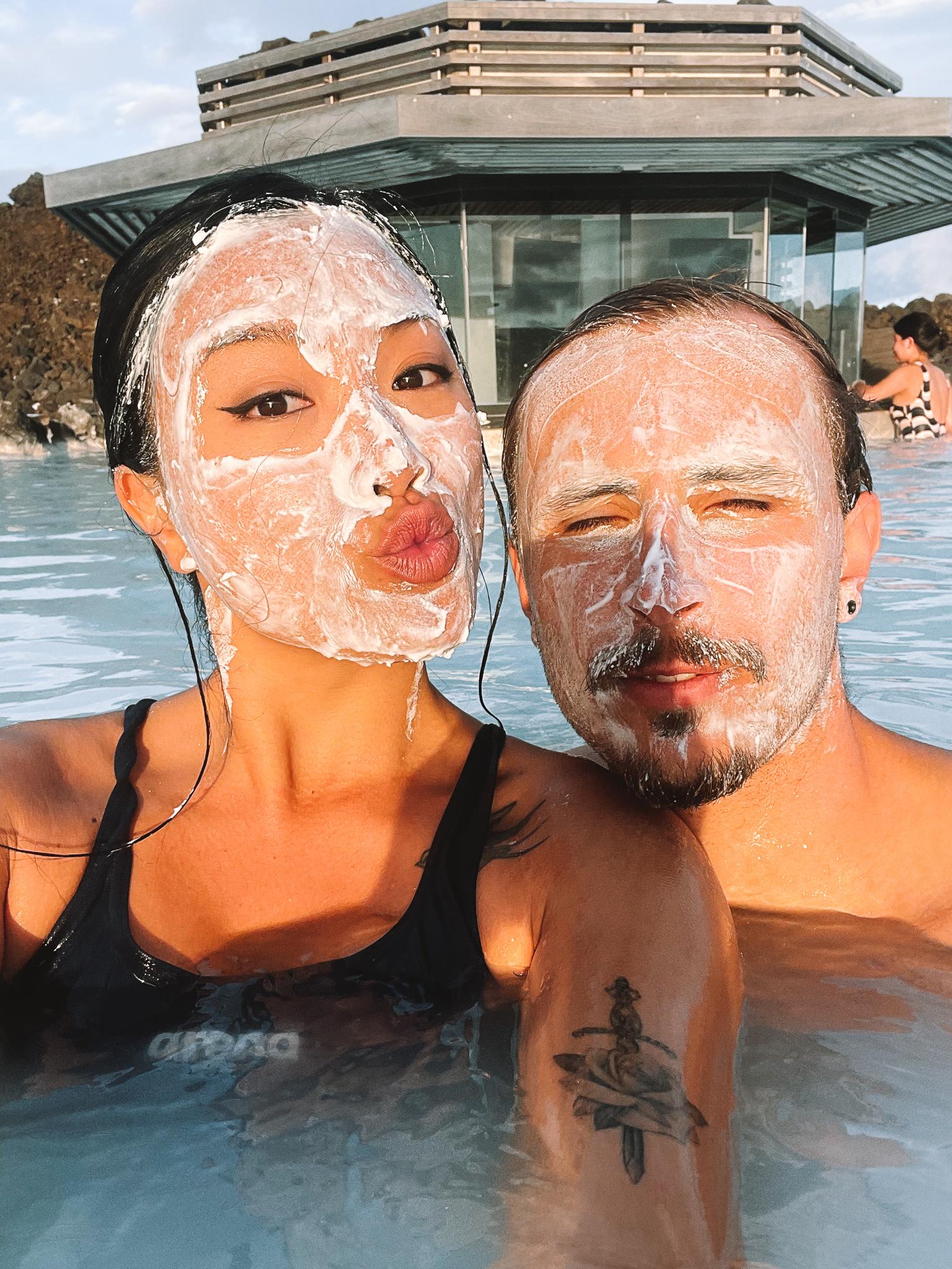 A man and woman using a silica mud mask at the Blue Lagoon in Iceland.